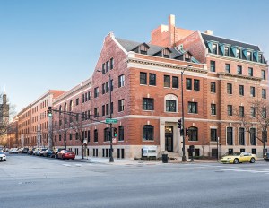 A red brick building on a street corner with Chicago's Sears Tower (Willis Tower) in the background