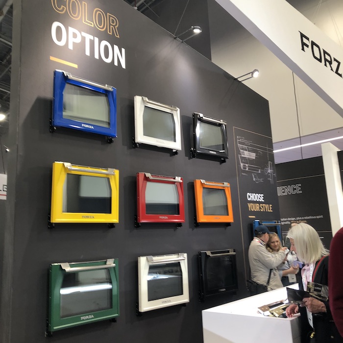 An array of different colored (red, blue, yellow, black, white, orange and green) oven doors arranged on a wall