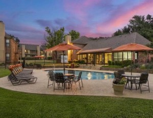 Apartment property exterior with pool at dusk