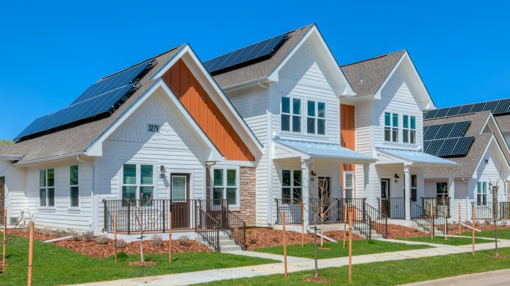 A row of houses featuring solar panels on their roofs, highlighting the adoption of sustainable energy practices.