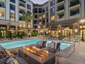 Exterior shot of Link OC Apartments pool area. The photo features lounge chairs and a firepit by the pool.