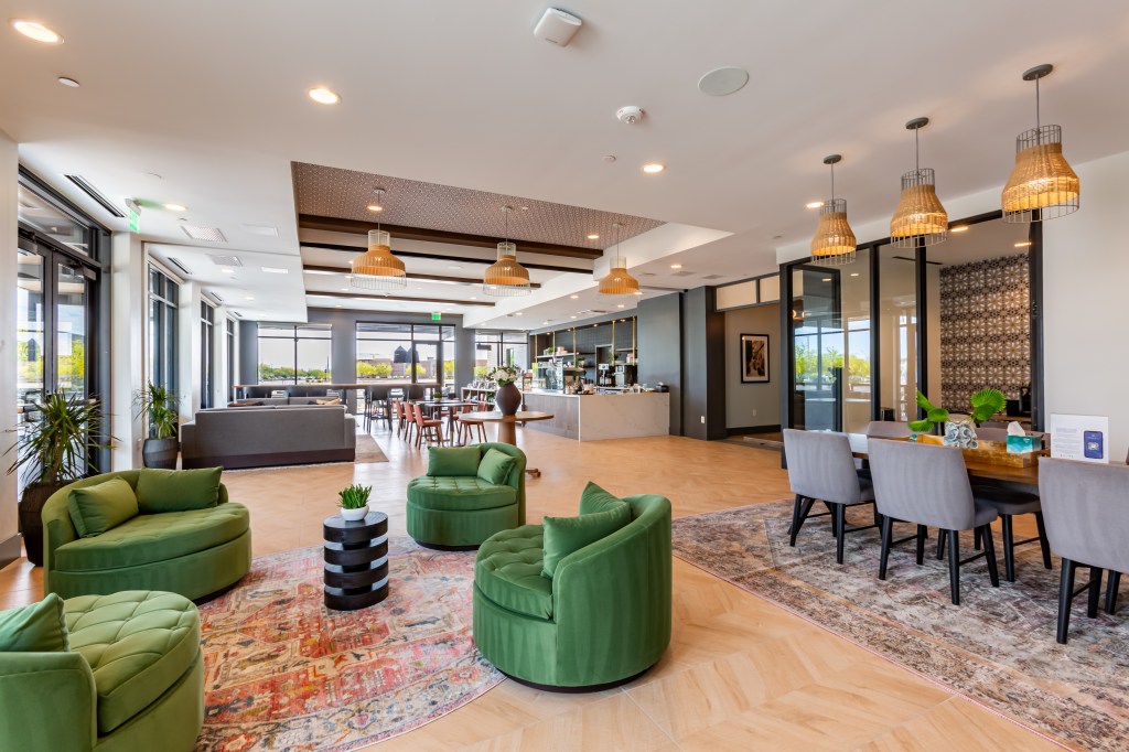 Interior shot of the lounge area at Novel Val Vista property in Phoenix. The photo features several sitting areas in an open space layout.