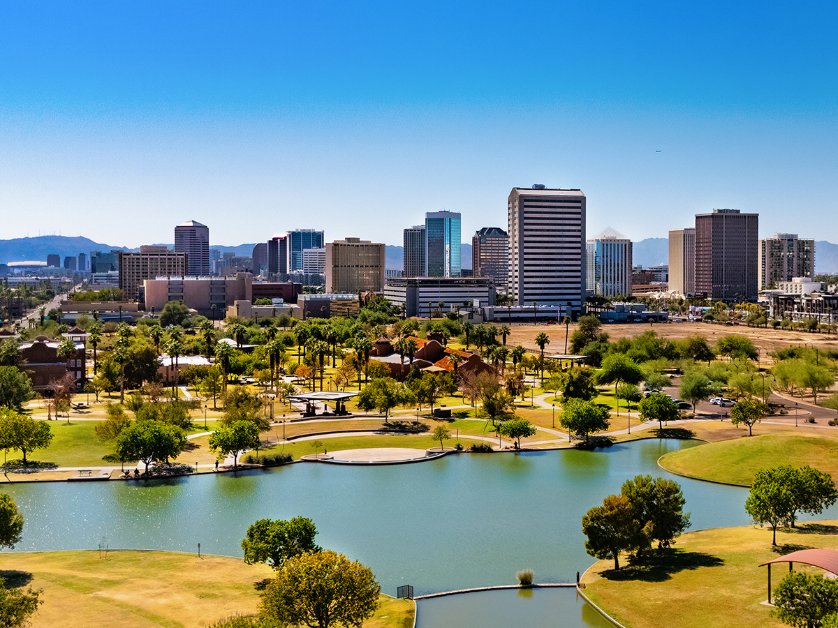 Elevated view of Midtown Phoenix skyline with a park with a lake and an American flag in the foreground.