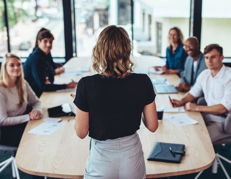 Leader talking to her team at a conference table.