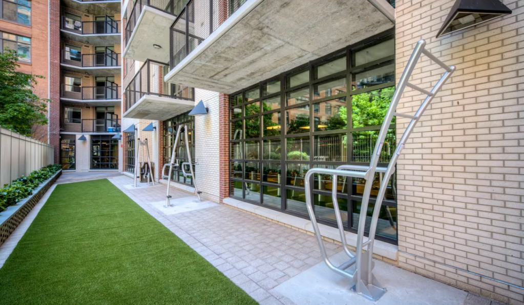 An image of AVA NoMa, an apartment community in Washington, D.C., showing an outdoor exercise area adjacent to the indoor gym.