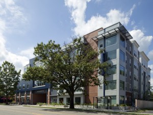 Exterior shot of Campus Circle, a student community in Urbana, Ill. The five-story building is surrounded by trees.