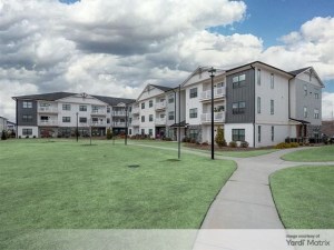 Exterior shot of the residential buildings within The Blakely. The three-story structure has a white and gray exterior and is surrounded by green lawns and walking paths.