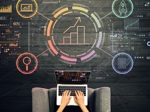Image displaying two hands typing on a laptop in the foreground and data visualization in the background.