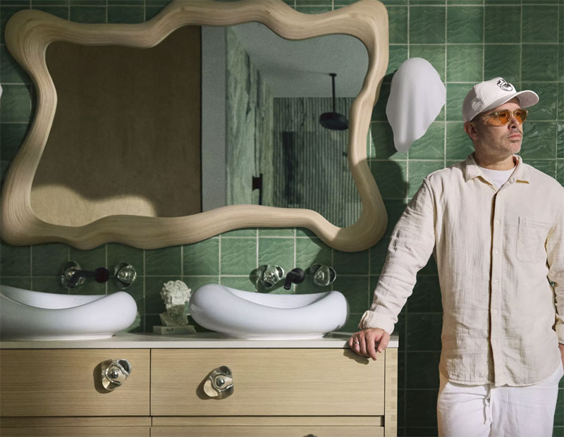 A man stands next to a bathroom vanity from the The Kohler x Arsham: Landshapes Collection.