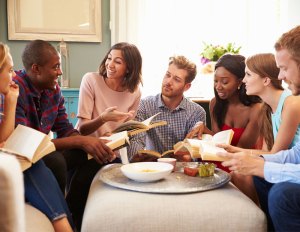 Group of people at a book club meeting holding books.