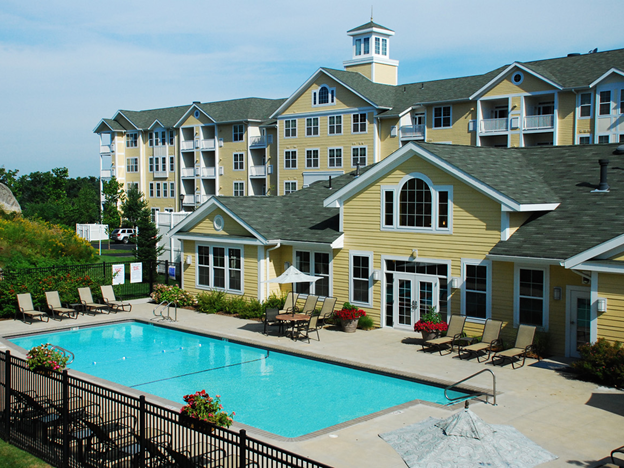Exterior shot of Lynnfield Commons, a 200-unit apartment community in Lynnfield, Mass. The image shows the community pool, as well as a part of one of the residential buildings.
