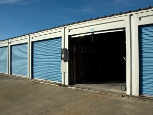 Exterior shot of a row of self storage units, out of which one is open.