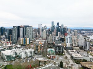 Aerial view of Seattle's downtown skyline with skyscrapers and waterfront on a cloudy day.