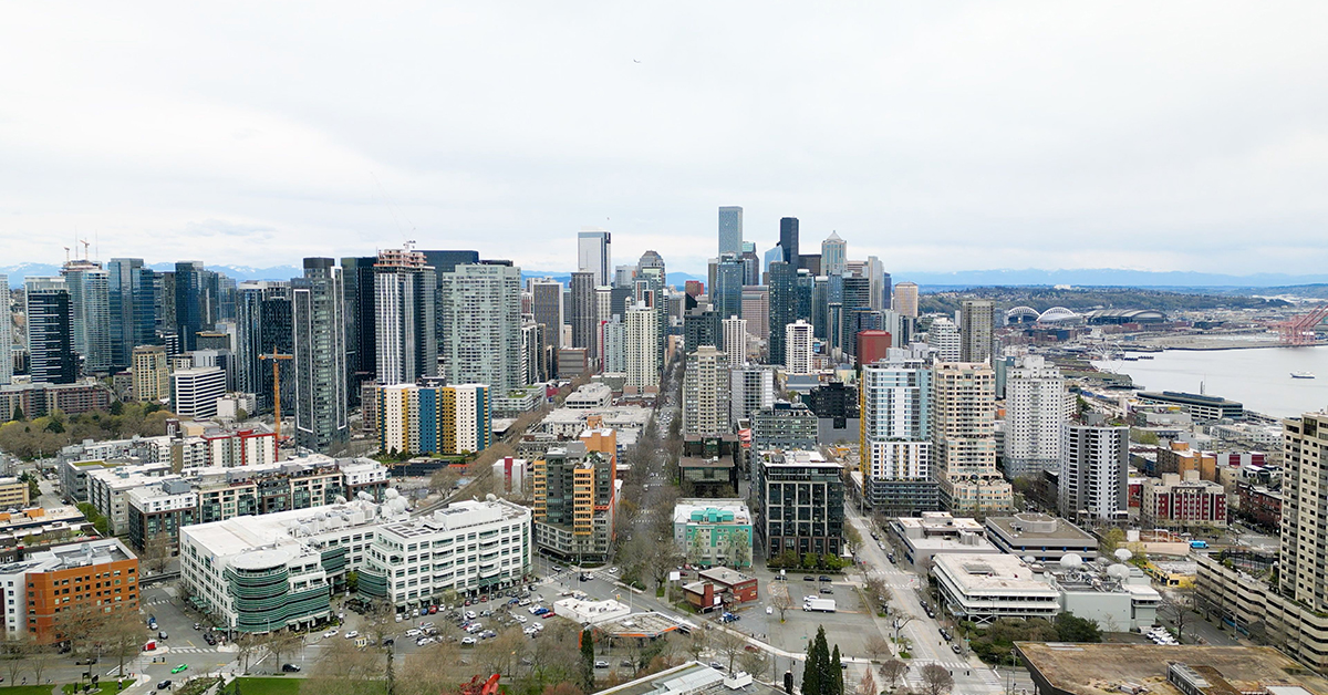 Aerial view of Seattle's downtown skyline with skyscrapers and waterfront on a cloudy day.