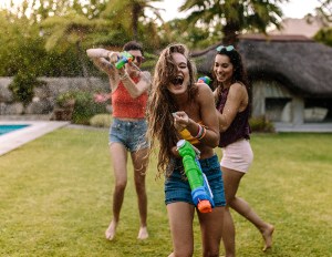 Three women playing with water guns.