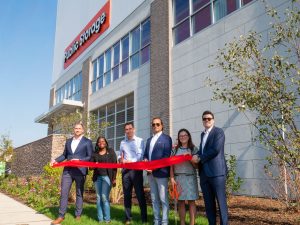 Exterior shot showing six individuals cutting a red ribbon at the grand opening of Jersey City Self Storage in Jersey City, N.J.