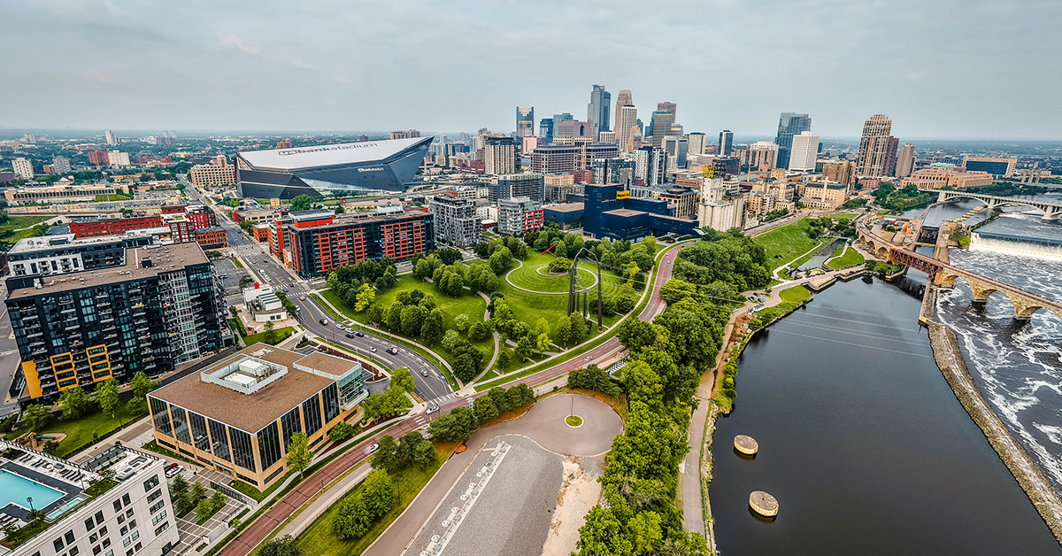 Minneapolis, MN, USA - June 10, 2025: Mississippi River, historic Stone Arch Bridge, US Bank Stadium, and modern skyscrapers