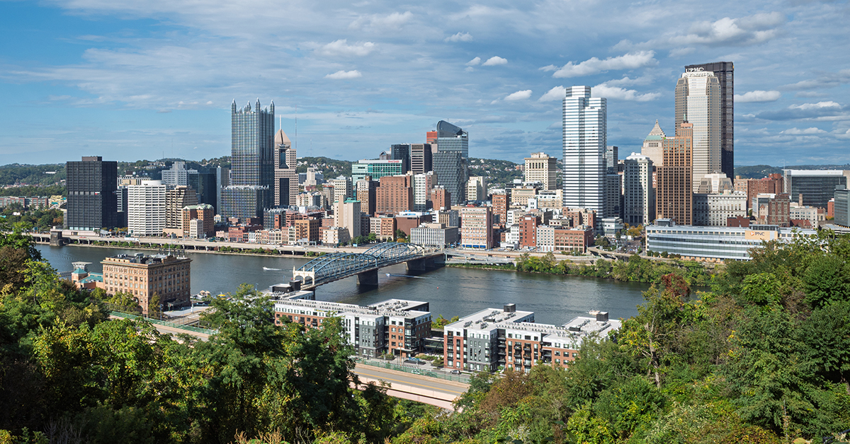 The Pittsburgh, Pennsylvania skyline with its iconic rivers and bridges under a dramatic blue sky.