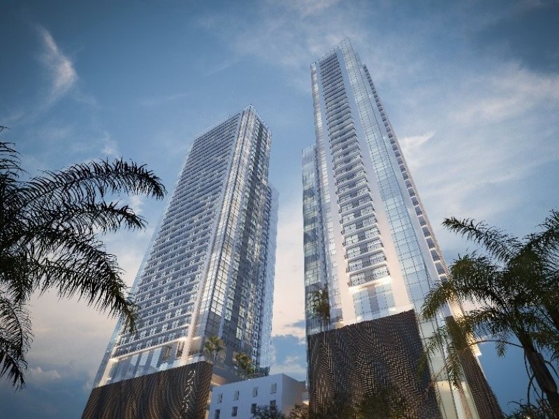 Street-level view of two high-rise towers flanked by palm trees.