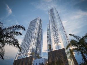 Street-level view of two high-rise towers flanked by palm trees.