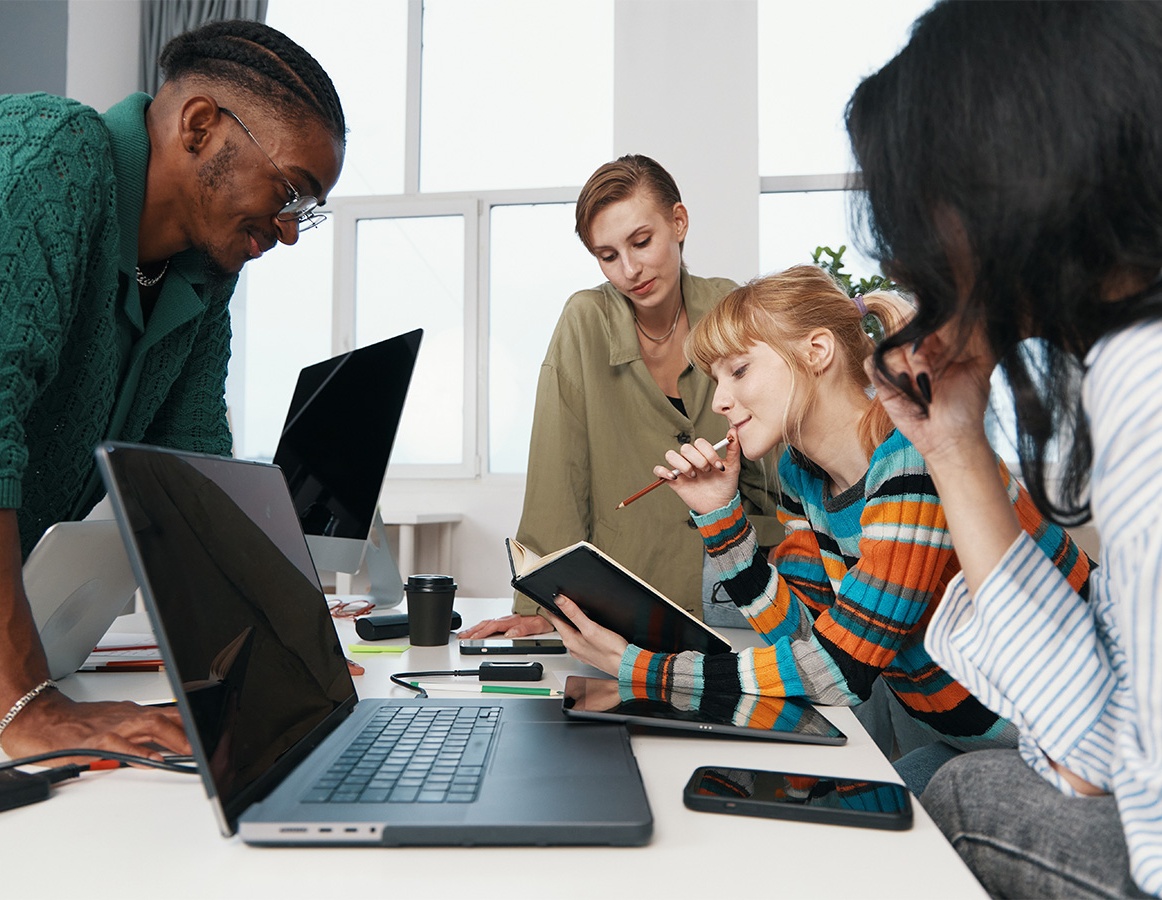 A team of young professionals working together on a laptop, exploring solutions for improving Gen Z employee retention.