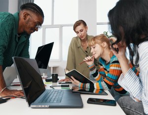 A team of young professionals working together on a laptop, exploring solutions for improving Gen Z employee retention.