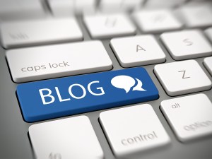 Online blog and blogspot concept with a blue enter button on a white computer keyboard with the word - Blog - and a chat icon , close up high angle view with blur vignette.