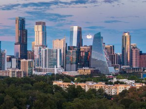 Aerial drone view of the Austin Texas skyline as the full harvest moon is seen rising by the office buildings. Zilker Park in the foreground.