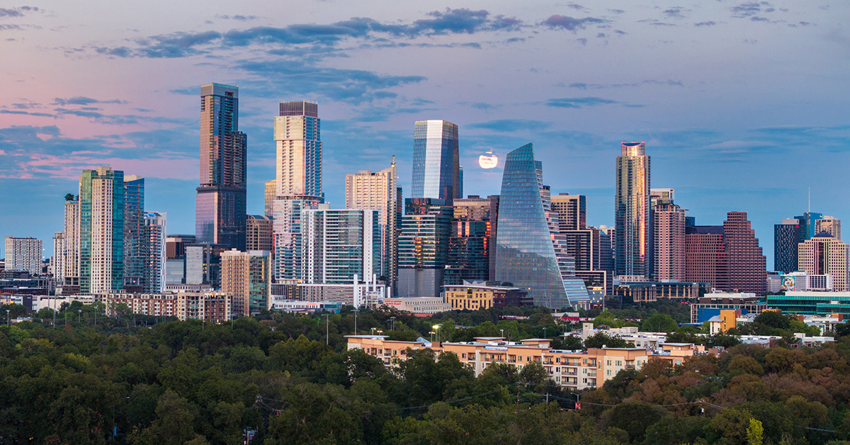Aerial drone view of the Austin Texas skyline as the full harvest moon is seen rising by the office buildings. Zilker Park in the foreground.