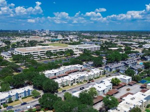 Blending of low rise flat roofed apartment complexes, multilevel parking structure from corporate campus, office buildings, major highways, and distant skyline background in Richardson, Texas. USA
