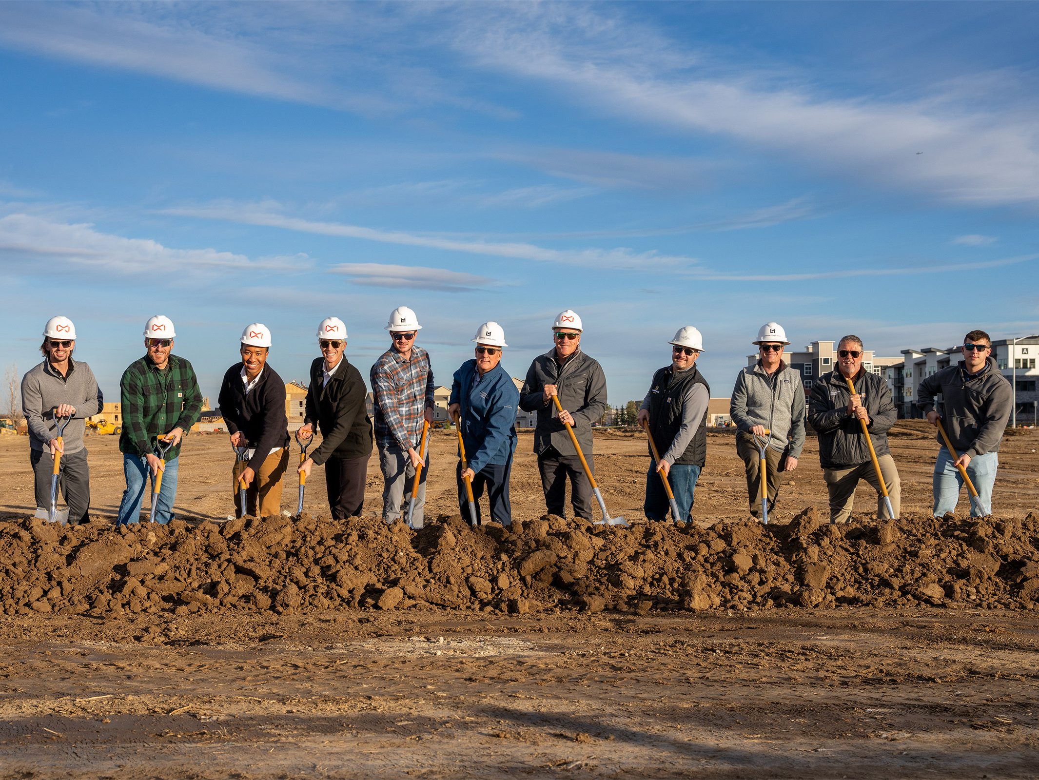 The picture shows a group of people at the groundbreaking ceremony for Mountain Brook Flats, in Longmont, Colo. From left to right: Tucker Isgrig, Cole Evans, Adrian Frank, Chad O’Connor, Chris Beabout, Jason Sherrill, Troy McWhinney, Chris Douglass, Cragon Sims, Jon Mosier, and Andrew Sherrill.