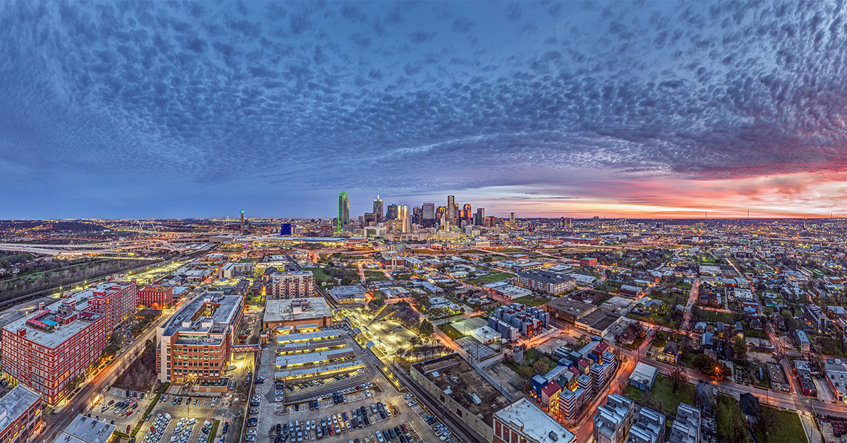 Colorful drone evening panorama of Dallas with dramatic sky and illuminated cityscape