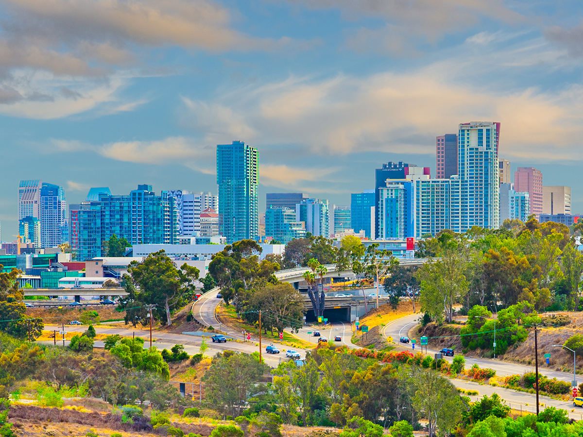 Lush foliage fills the hillside in front of San Diego skyline which is a city on the Pacific coast of California known for its beaches, parks and warm climate