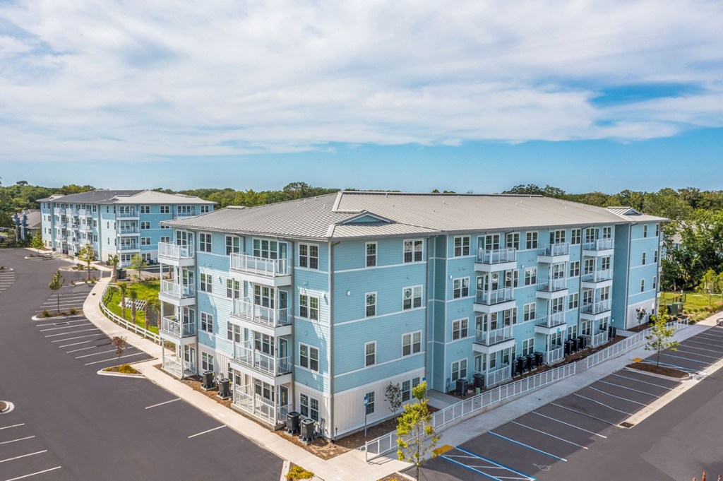 An aerial photograph of a coastal-themed apartment community, with blue walls and white trim and balcony railings.