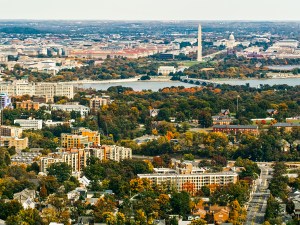 Helicopter shot of Washington, D.C. on a hazy afternoon in Fall from over Arlington, VA, looking across the city towards the Washington Monument and the Capitol Building.