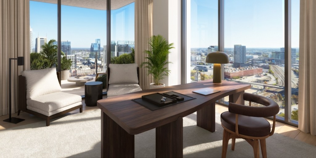 Modern office with a panoramic city view through large windows. Features a wooden desk, a cushioned armchair, and plants, creating a calm and elegant atmosphere.