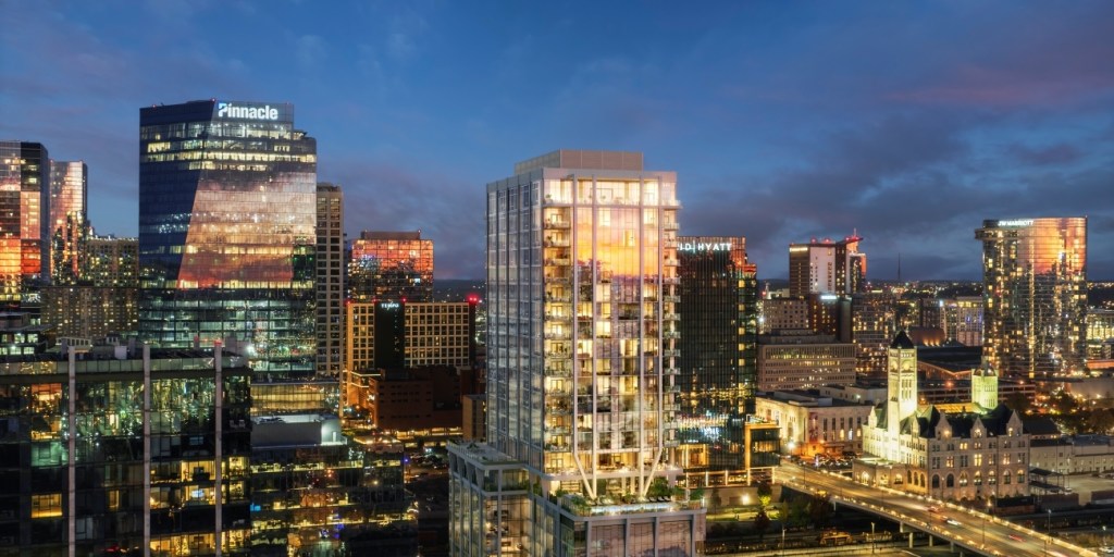 A vibrant city skyline at dusk features illuminated skyscrapers and office buildings with reflective windows. A mix of lights and clouds adds a lively urban feel.