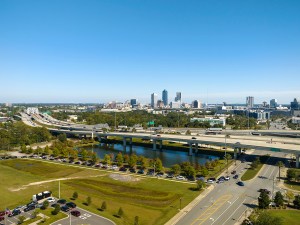 Aerial view of Jacksonville city with high office buildings and american freeway intersection with fast moving cars and trucks. USA transportation infrastructure concept.