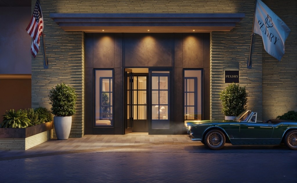 Entrance of an upscale building at dusk with American and "Pendry" flags. A vintage green convertible is parked in front, evoking an elegant, inviting atmosphere.