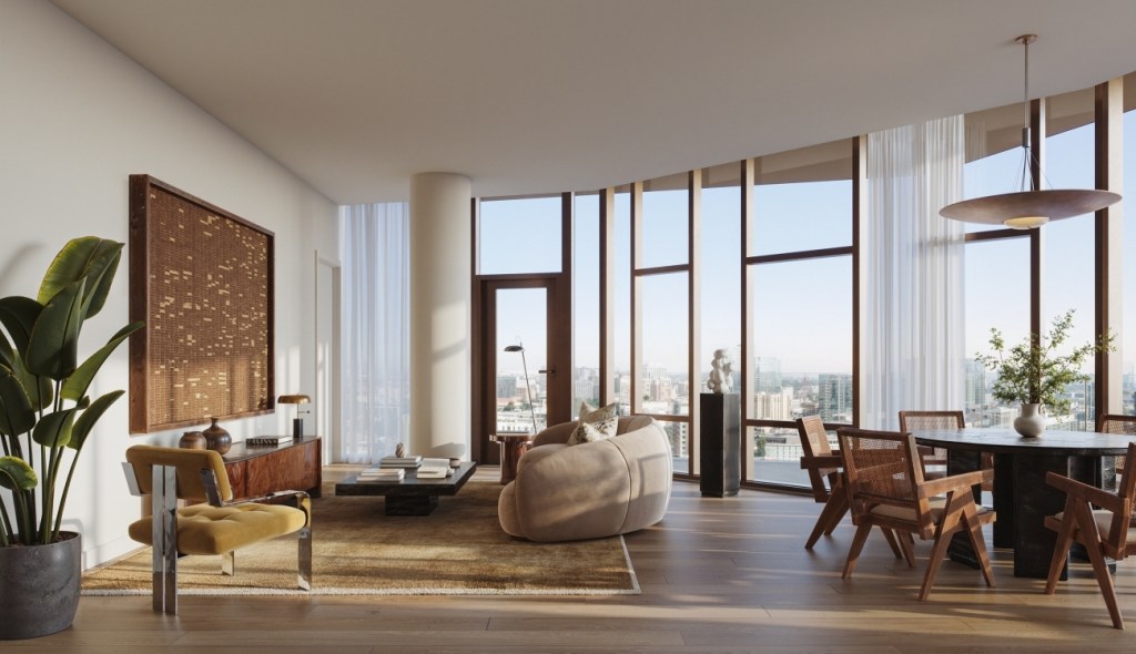 A modern living room with floor-to-ceiling windows, a beige sofa, and wooden furniture. Natural light and greenery create a serene and airy atmosphere.
