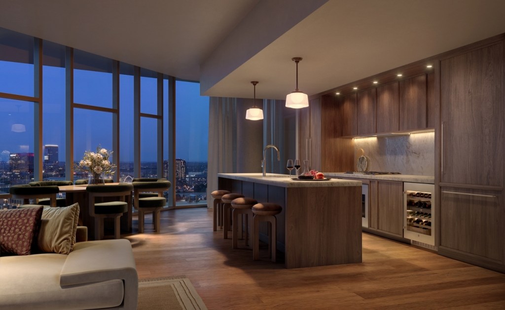 Sophisticated open-concept kitchen and dining area with city view. Features wooden cabinetry, marble backsplash, pendant lighting, and evening ambiance.