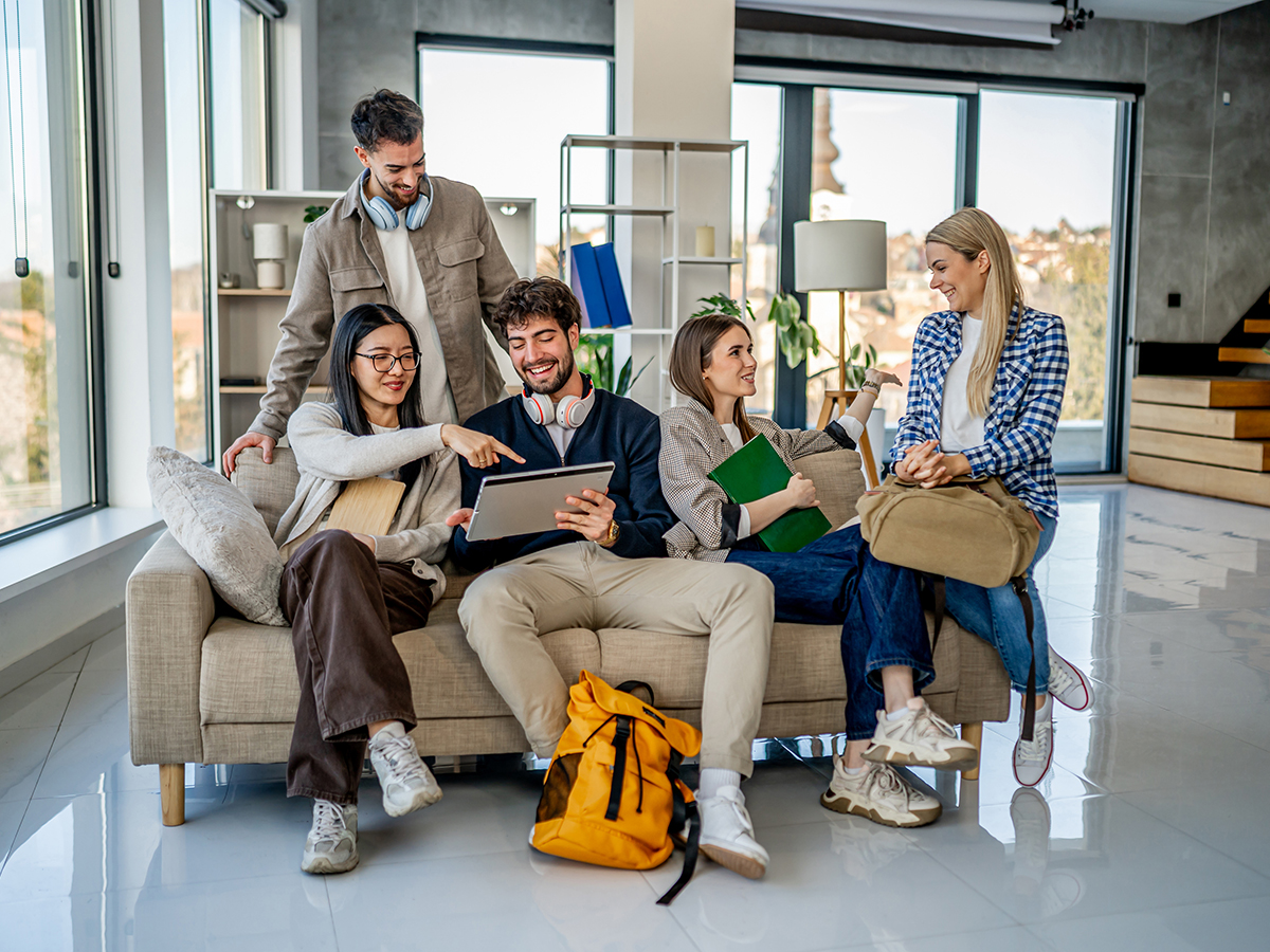 Group of diverse young adults are studying and collaborating together, using a digital tablet for their university project