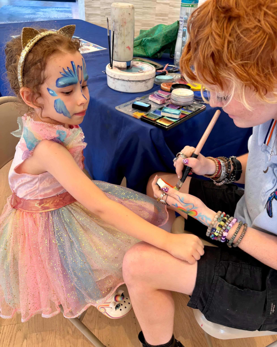 Child getting face paint at a resident event inside an apartment community.