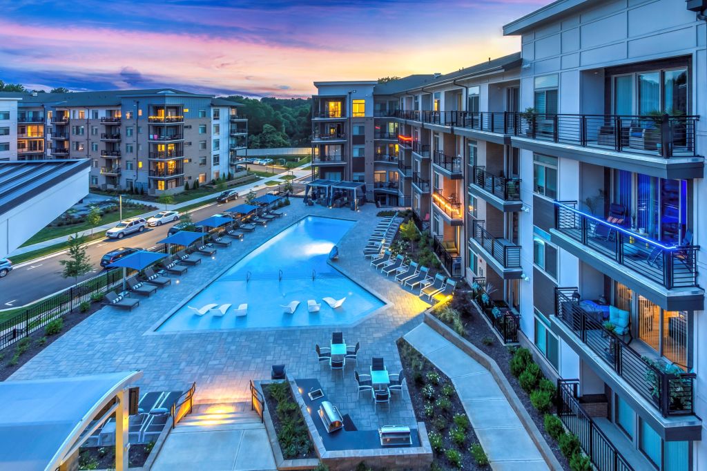 Twilight view of The Abbey apartment community with pool, lit balconies and shared outdoor spaces. For Evolution of Multifamily Marketing article.