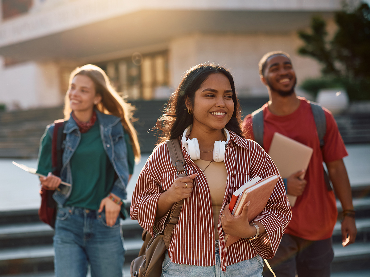 Happy Indian student going on a lecture at the university. Her friends are in the background.