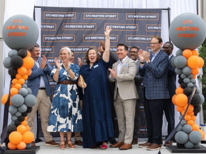 Exterior shot capturing the grand opening ceremony at 573 Meeting Street, attended by officials from The Michaels Organization, One80 Place and Spandrel Development.