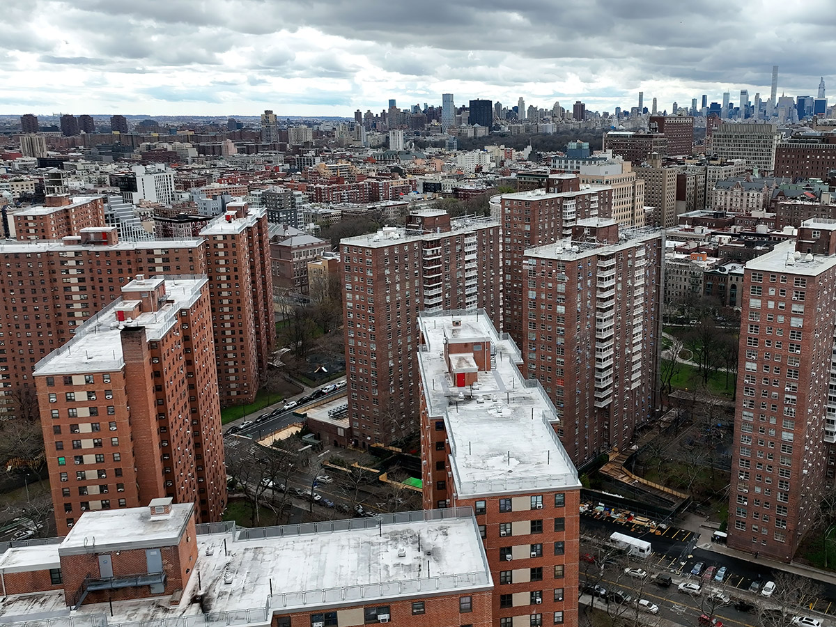 Exterior shot depicting Harlem NYC affordable housing projects with Manhattan skyline.