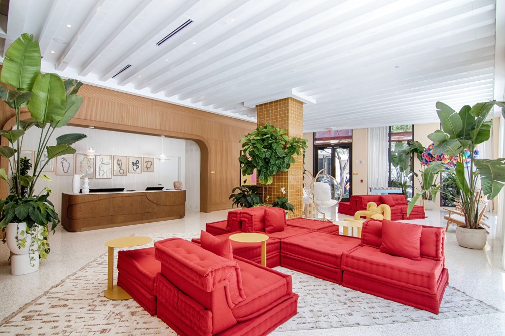 lobby featuring red couches and decorative plants, creating a welcoming and stylish atmosphere for residents