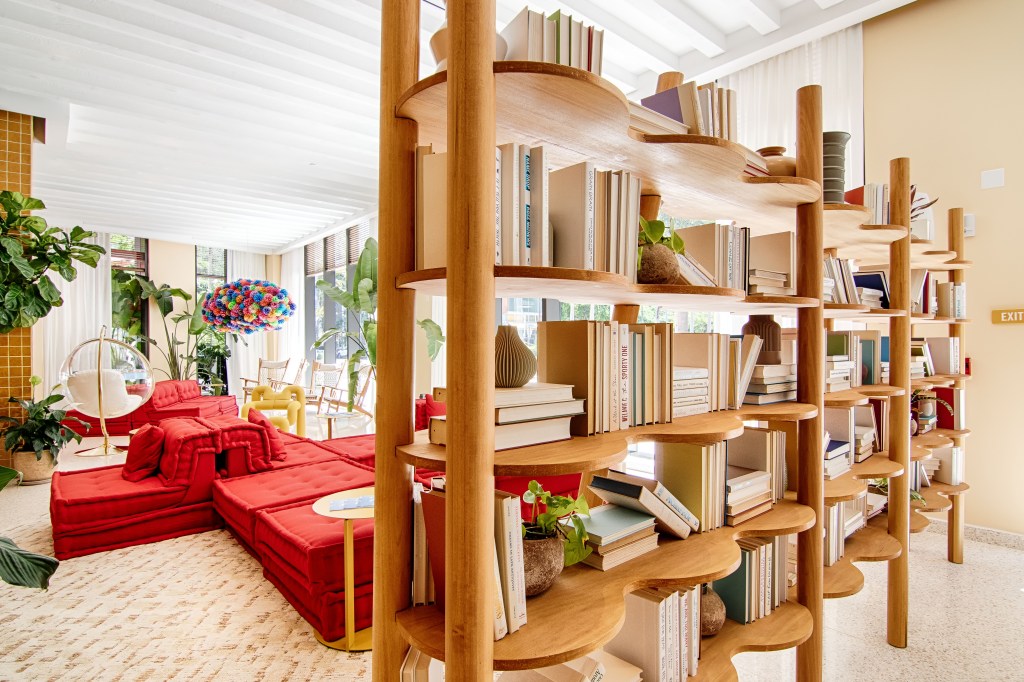 A stylish apartment lobby with vibrant red couches and lush plants, designed for comfort and relaxation.
