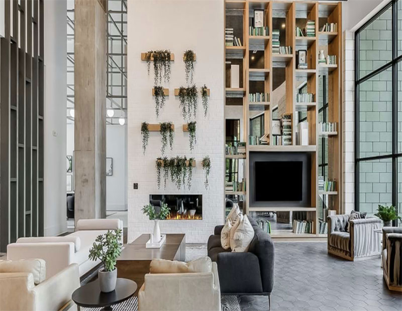 An amenity space at Halcyon Grand in Alpharetta, Ga., with a biophilic wall, seating, a fireplace and natural light.